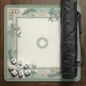 May include: A rectangular Mahjong game mat with a cream-colored center and a light green border. The border features a floral and bamboo design. A black carrying case is on the right side. Several white Mahjong tiles are visible on the mat.
