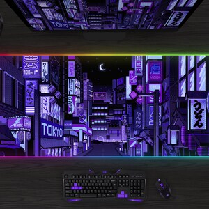 May include: A rectangular gaming mouse pad with a pixelated Tokyo cityscape design in shades of purple and blue. The pad has a glowing, multi-colored edge. A keyboard, mouse, and headset are also visible.