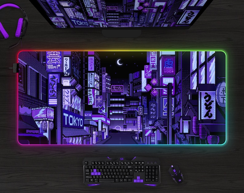 May include: A rectangular gaming mouse pad with a pixelated Tokyo cityscape design in shades of purple and blue. The pad has a glowing, multi-colored edge. A keyboard, mouse, and headset are also visible.