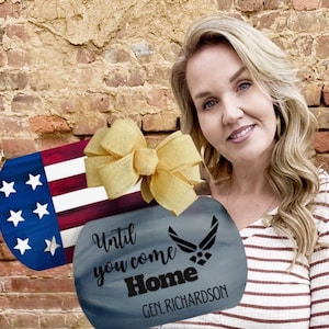 May include: A wooden dog tag-shaped sign with an American flag design and a bow. The second tag is blue with the text "Until you come Home" and an Air Force emblem. The sign is personalized with the name "GEN. RICHARDSON".