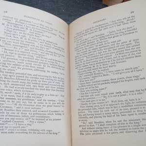 Puede incluir: Un libro abierto con p&aacute;ginas amarillentas y texto impreso. Las p&aacute;ginas est&aacute;n envejecidas, lo que sugiere la edad. El libro parece ser un texto hist&oacute;rico o una novela, con t&iacute;tulos de cap&iacute;tulos visibles.