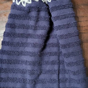 May include: A blue striped kitchen towel with a white crocheted loop and a blue button.