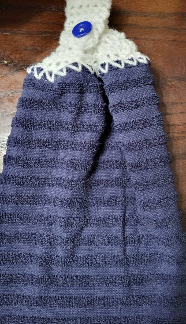May include: A blue striped kitchen towel with a white crocheted loop and a blue button.