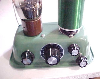 May include: A green metal box with a vacuum tube, a coil, and three knobs. The box has a dial with numbers from 0 to 60.