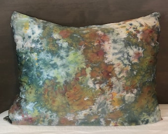 May include: A decorative pillow with a green, brown, and white abstract pattern. The pillow is made of silk and has a soft, luxurious feel.