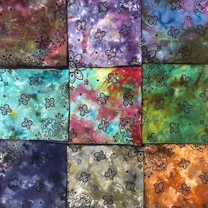 Puede incluir: Una colección de nueve pañuelos de tela cuadrados dispuestos en una cuadrícula, cada uno con un patrón de color tie-dye único y un estampado de cachemira negro constante. Los colores incluyen tonos de morado, azul, turquesa, rojo, amarillo, verde y naranja.