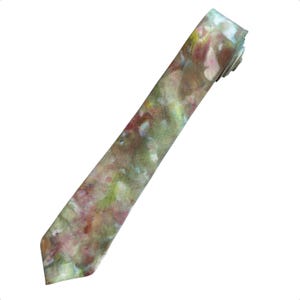 May include: A necktie featuring an abstract watercolor-style print with blended patches of muted green, soft pink, deep burgundy, and creamy white tones. The fabric displays a smooth, matte texture with a pointed tip and a folded top section.
