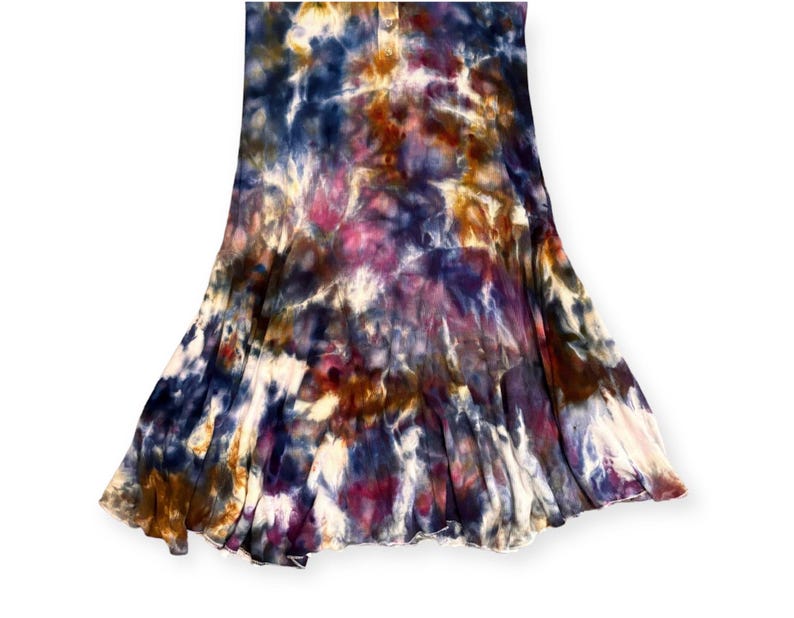 Pode incluir: Uma saia tie-dye em tons de azul, roxo, castanho e branco. A saia tem uma silhueta rodada, com as cores misturando-se num padr&atilde;o &uacute;nico. O tecido parece macio e fluido.