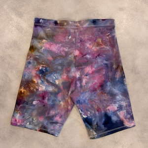 May include: Purple, blue, and brown tie-dye bike shorts. The shorts have a stretchy, comfortable fit.