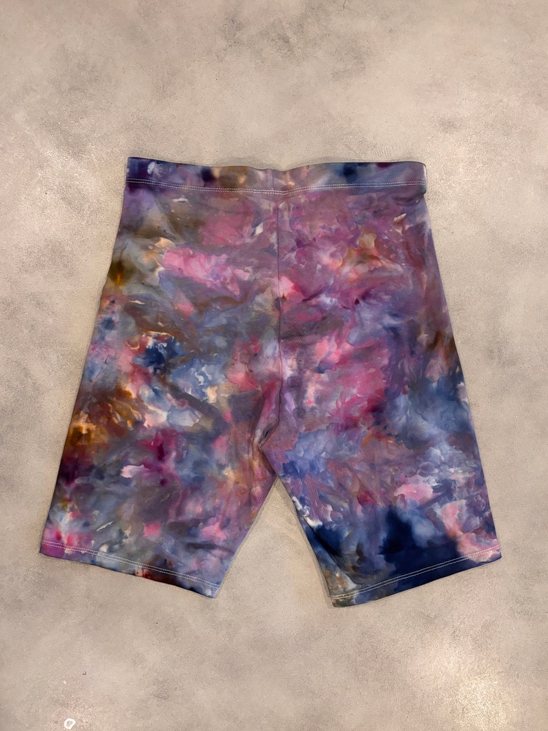 May include: Purple, blue, and brown tie-dye bike shorts. The shorts have a stretchy, comfortable fit.