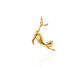 May include: A gold-toned pendant charm in the shape of a cat, with the cat's tail curled up over its back. The cat is facing to the right and appears to be jumping or stretching.