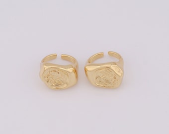 May include: Two gold-toned rings with a textured, square-shaped design. Each ring features a raised, detailed design on the front.