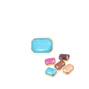 May include: Assortment of colorful glass gems with gold settings. The gems are rectangular and have a faceted design. The colors include turquoise, pink, brown, and burgundy.