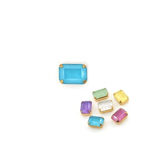 May include: Assortment of colorful rectangular glass rhinestones with gold settings. The rhinestones are in shades of blue, green, yellow, purple, pink, and clear.