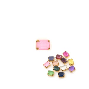 May include: Assortment of colorful glass gems with gold settings. The gems are rectangular and have a faceted finish.