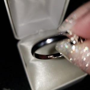 May include: A silver ring with a band of small diamonds set in a white ring box.