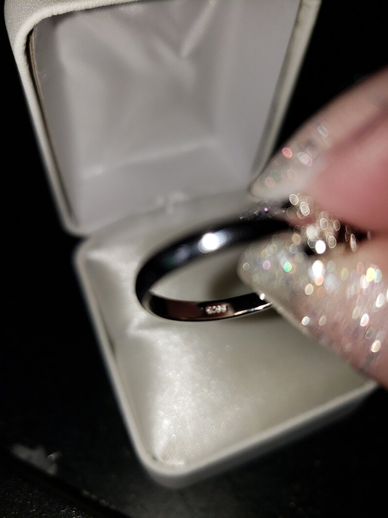 May include: A silver ring with a band of small diamonds set in a white ring box.