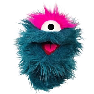 May include: A teal furry monster puppet with a pink mohawk and a large white eye with a black pupil. The puppet has a pink heart-shaped tongue and a red mouth.