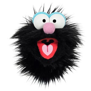 May include: A plush, round monster puppet with black fur, large white eyes, and a pink nose. The mouth is open, revealing a red interior with a pink heart shape. Blue accents frame the eyes.