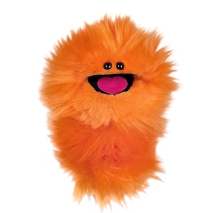 May include: A bright orange plush puppet covered in long, shaggy faux fur. The puppet features two small, round black eyes positioned above a wide, open black mouth containing a prominent, rounded pink tongue centred within the dark opening.