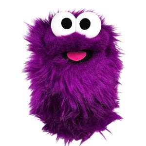 Op de afbeelding: Een paarse pluche monsterhandpop met lang, ruig imitatiebont. De pop heeft twee grote, ronde witte ogen met zwarte pupillen, een wijd open mond met een zwarte binnenkant en een kleine, felroze tong zichtbaar in de mondopening.