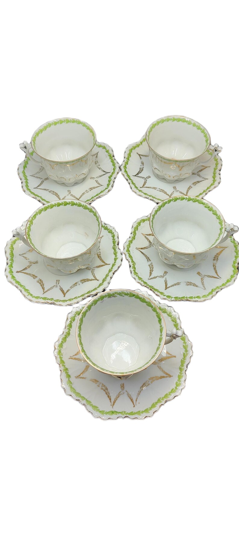 May include: Set of five white teacups and saucers. Each cup and saucer features a scalloped edge with green and gold leaf accents. The cups have a delicate, embossed design.