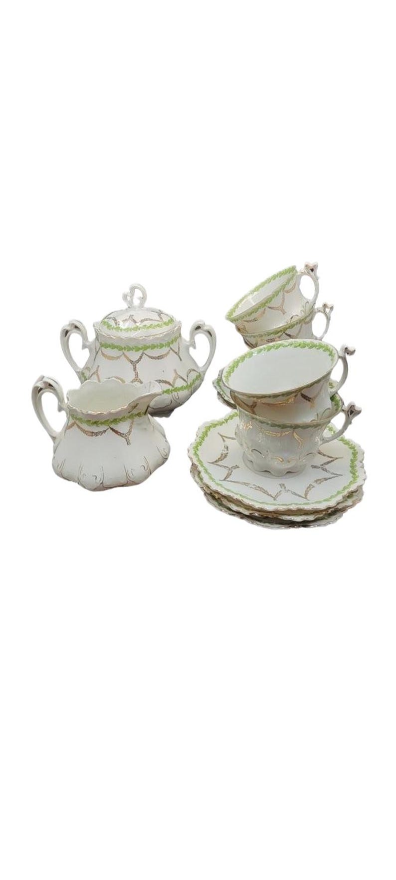 May include: A white porcelain tea set with gold trim and green accents. The set includes teacups, saucers, a sugar bowl with a lid, and a creamer. The tea set has a delicate, vintage design.