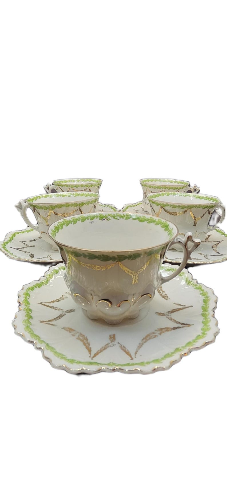 May include: A set of six antique teacups and saucers. The cups and saucers are white with gold and green leaf designs. The saucers have a scalloped edge.
