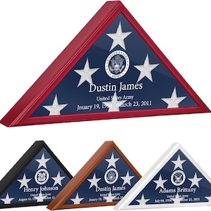 Może przedstawiać: Trzy drewniane ramki z cieniowaniem z złożoną flagą amerykańską w środku. Ramki są czerwone, brązowe i białe. Każda ramka zawiera imię, rodzaj służby i daty służby.