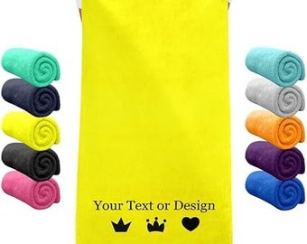 Puede incluir: Una toalla de playa de color amarillo brillante con el texto "Your Text or Design" y tres iconos negros: una corona, una corona y un corazón. La toalla está enrollada en varios colores, incluyendo azul, verde, rosa y naranja.