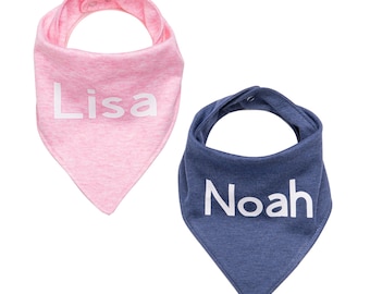 Può includere: Due bavaglini per bambini. Uno è rosa con il nome "Lisa" in bianco, e l'altro è blu con il nome "Noah" in bianco. Entrambi i bavaglini hanno chiusure a scatto sul collo e sono di forma triangolare.