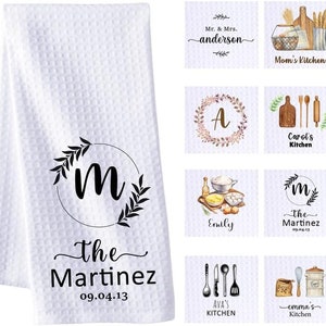 Peut inclure: Un ensemble de 10 torchons de cuisine avec un fond blanc et un motif de couronne florale. Chaque torchon présente une initiale différente et le texte "Cuisine". Les torchons sont personnalisés avec des noms et des dates.