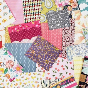 May include: A colorful assortment of patterned fabric squares. Designs include rainbows, polka dots, florals, cherries, and geometric shapes. The fabrics are in shades of pink, blue, yellow, green, and purple, creating a vibrant and cheerful display.