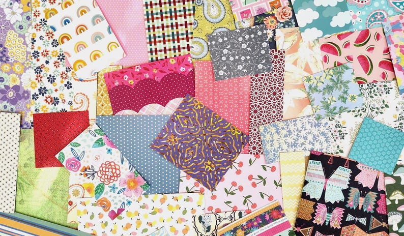 May include: A colorful assortment of patterned fabric squares. Designs include rainbows, polka dots, florals, cherries, and geometric shapes. The fabrics are in shades of pink, blue, yellow, green, and purple, creating a vibrant and cheerful display.