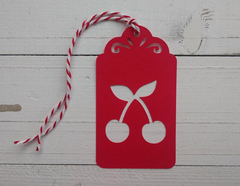 May include: Red gift tag with a white cherry design and a white and red twine string.