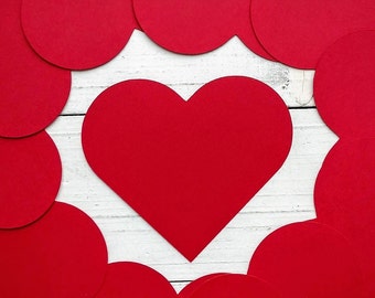 May include: A red heart shape surrounded by a border of smaller red circles on a white background.