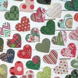 May include: A collection of heart-shaped paper cutouts with various patterns and designs. The hearts are in shades of red, green, blue, and white. Some hearts have polka dots, stripes, and floral patterns. Others have words or phrases printed on them.