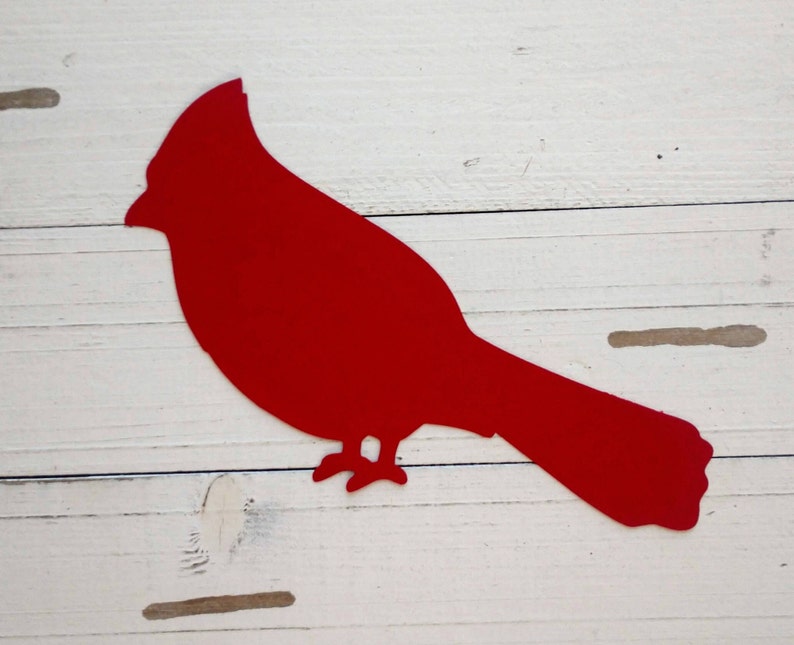 May include: Red cardinal bird silhouette cut out of metal. The bird is facing right and has a long tail.