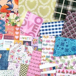 May include: A collection of patterned paper sheets in various designs and colors. Includes floral, geometric, and text-based patterns. The color palette features pinks, blues, greens, and oranges. Some sheets have the word "LOVE" printed on them.