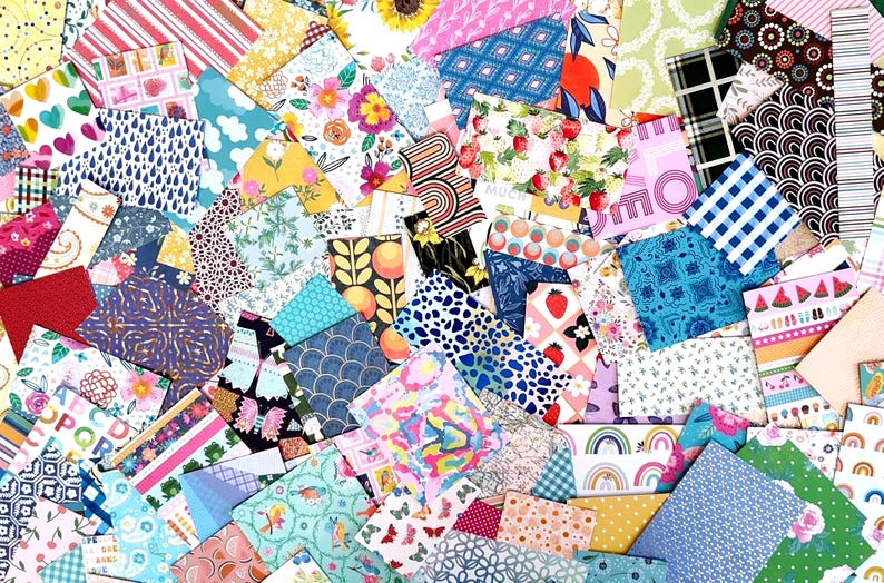 May include: A vibrant assortment of patterned paper sheets in various colors and designs. The collection includes floral, geometric, and fruit patterns, with some sheets featuring text. The papers are arranged in a layered, overlapping composition.