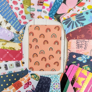 May include: A collection of colorful patterned cards with various designs, including rainbows, strawberries, and floral patterns. The cards are arranged in a circle on a white surface.