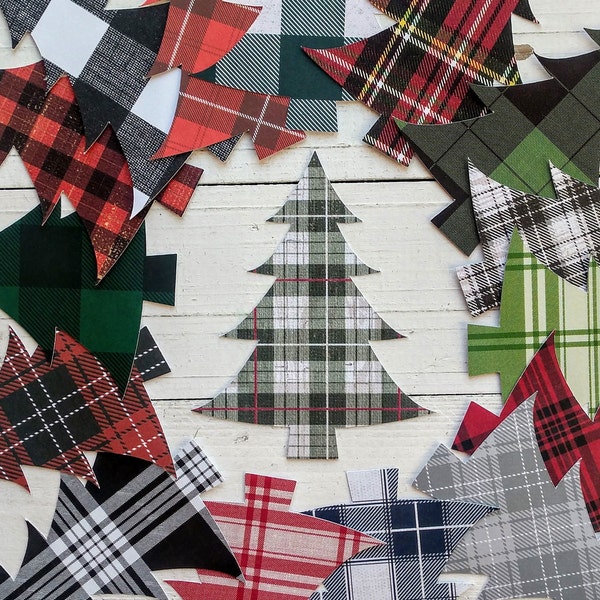 May include: A collection of plaid Christmas tree cutouts in various colors and patterns, including red, green, black, and white. The trees are arranged on a white wooden surface, creating a festive holiday theme.
