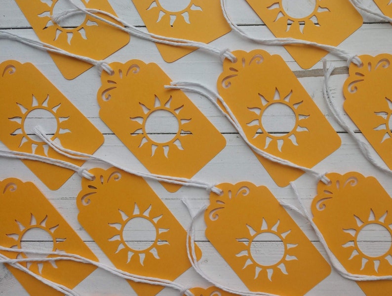 May include: A set of ten yellow gift tags with a white sun cut-out design. Each tag has a white string attached.