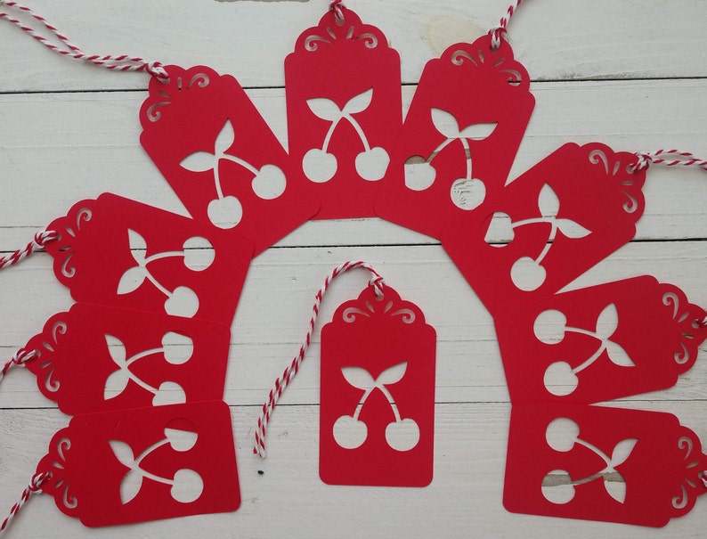 May include: Ten red gift tags with white cherry designs and white twine. The tags have a scalloped edge and are perfect for adding a festive touch to gifts.