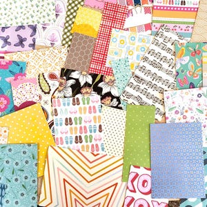 May include: A collection of colorful patterned paper sheets. Designs include strawberries, butterflies, musical notes, floral patterns, and geometric shapes. The papers are in various sizes and colors, creating a vibrant collage.