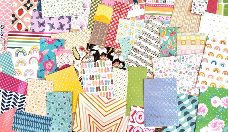 May include: A collection of colorful patterned paper sheets. Designs include strawberries, butterflies, musical notes, floral patterns, and geometric shapes. The papers are in various sizes and colors, creating a vibrant collage.
