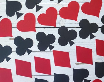 May include: A white background with red and black card shapes. The shapes are hearts, diamonds, clubs, and spades. The shapes are arranged in a random pattern.