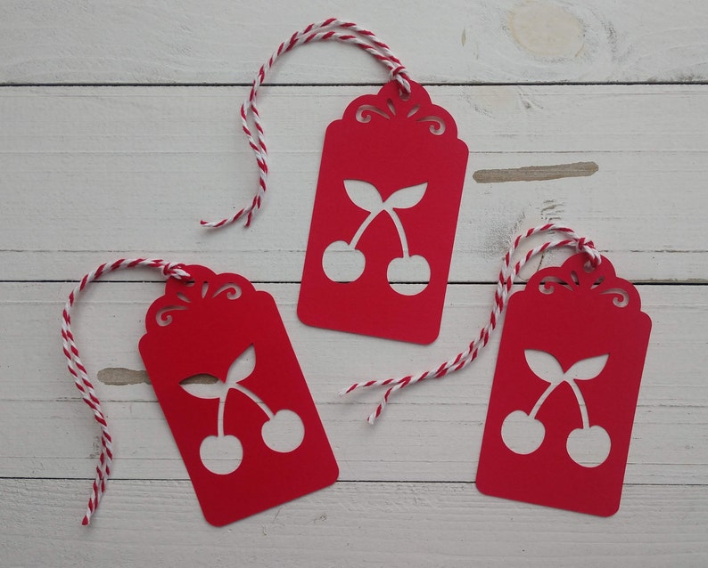 May include: Three red gift tags with white cherry designs and white and red twine.