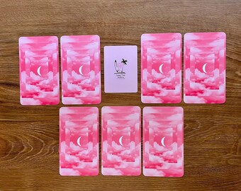 May include: Seven rectangular cards arranged in a spread. Six cards feature a pink sky with clouds and a white crescent moon. One central card is light pink with a black graphic of a surfboard, palm tree, and the text Island Time Wellness.