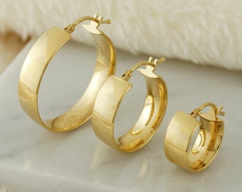May include: Three gold hoop earrings of different sizes. The earrings are on a white surface.